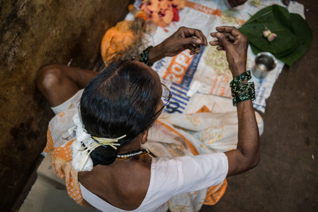 Woman making flower garlands at Mapusa Market, Goa